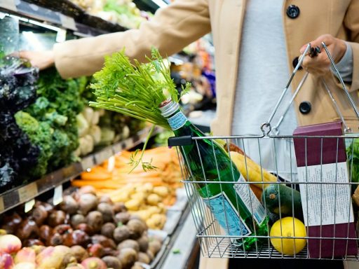 woman in white coat holding green shopping cart