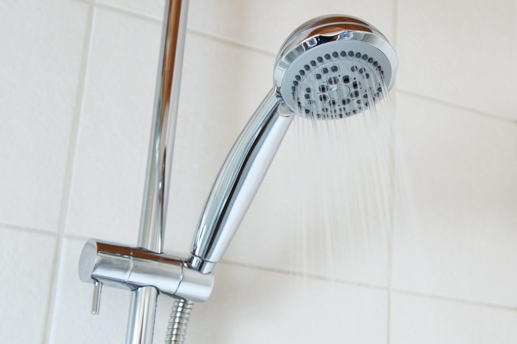 Iemand die de watermeter afleest in een Belgische woning om het waterverbruik te controleren