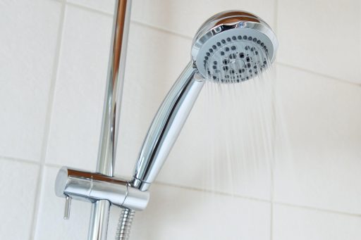 Iemand die de watermeter afleest in een Belgische woning om het waterverbruik te controleren