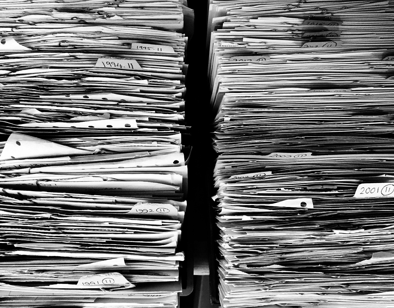 Smartphone met digitale bonnetjes naast een stapel papieren kassatickets op een bureau