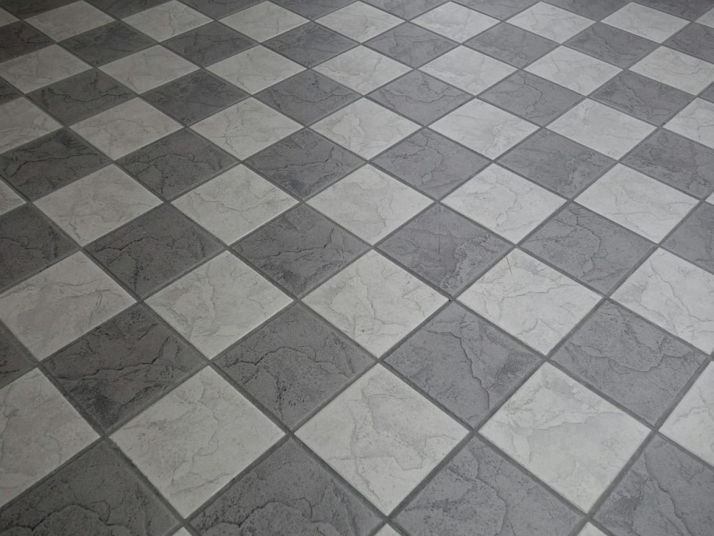 Hand die een tapijttegel legt op een kale vloer naast bestaande tapijttegels