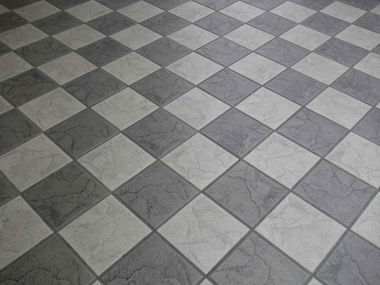 Hand die een tapijttegel legt op een kale vloer naast bestaande tapijttegels