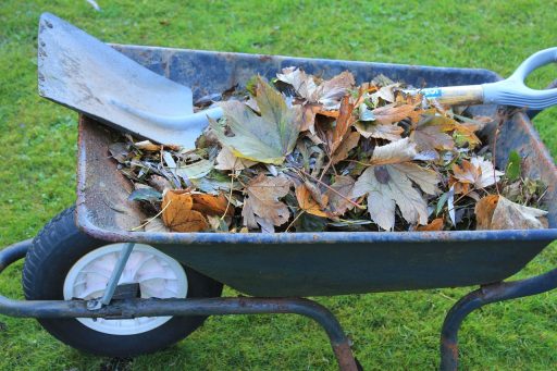 Een houten compostbak gevuld met herfstbladeren in een Belgische tuin