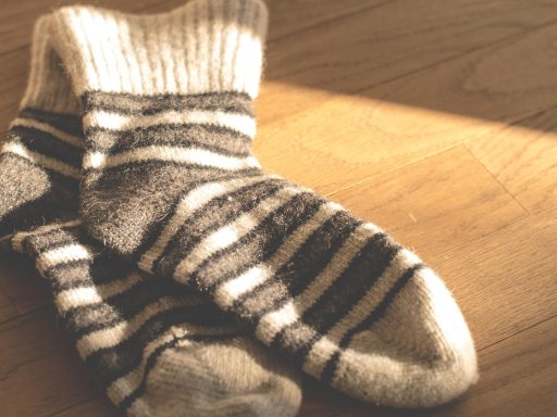 Dikke geitenwollen sokken in warm beige en grijs op een houten vloer
