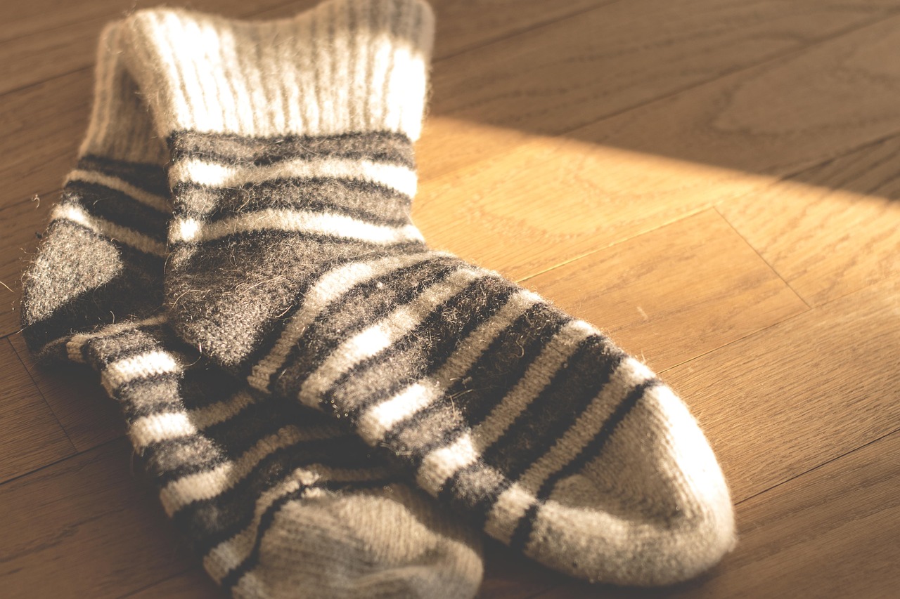Dikke geitenwollen sokken in warm beige en grijs op een houten vloer